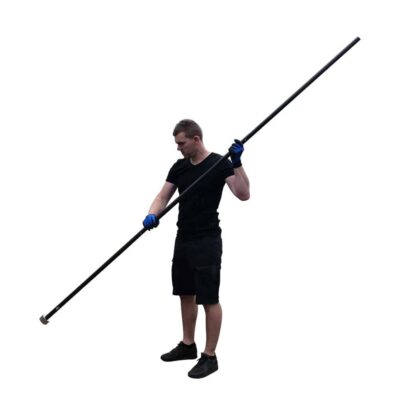 Lifestylefoto van man in zwarte outfit met blauwe werkhandschoenen die een lange aluminium prikstok met vismagneet vasthoudt.