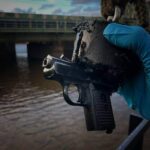 Lifestylefoto van een vismagneet die een modderige metalen vuurwapen uit het water heeft gehaald tijdens magneetvissen.