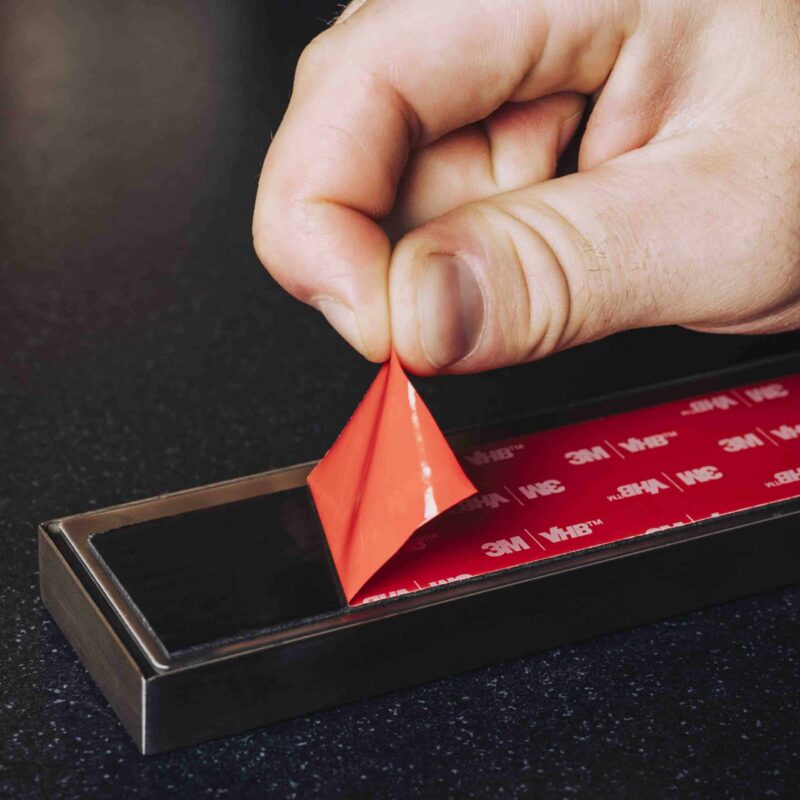 Close-up van montage van magnetische messenstrip met dubbelzijdige 3M plakstrip voor eenvoudige bevestiging zonder boren.