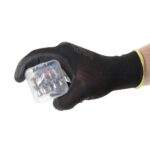 Hand met zwarte werkhandschoen die een doorzichtige kunststof doos met meerdere kleine neodymium pionmagneten vasthoudt.