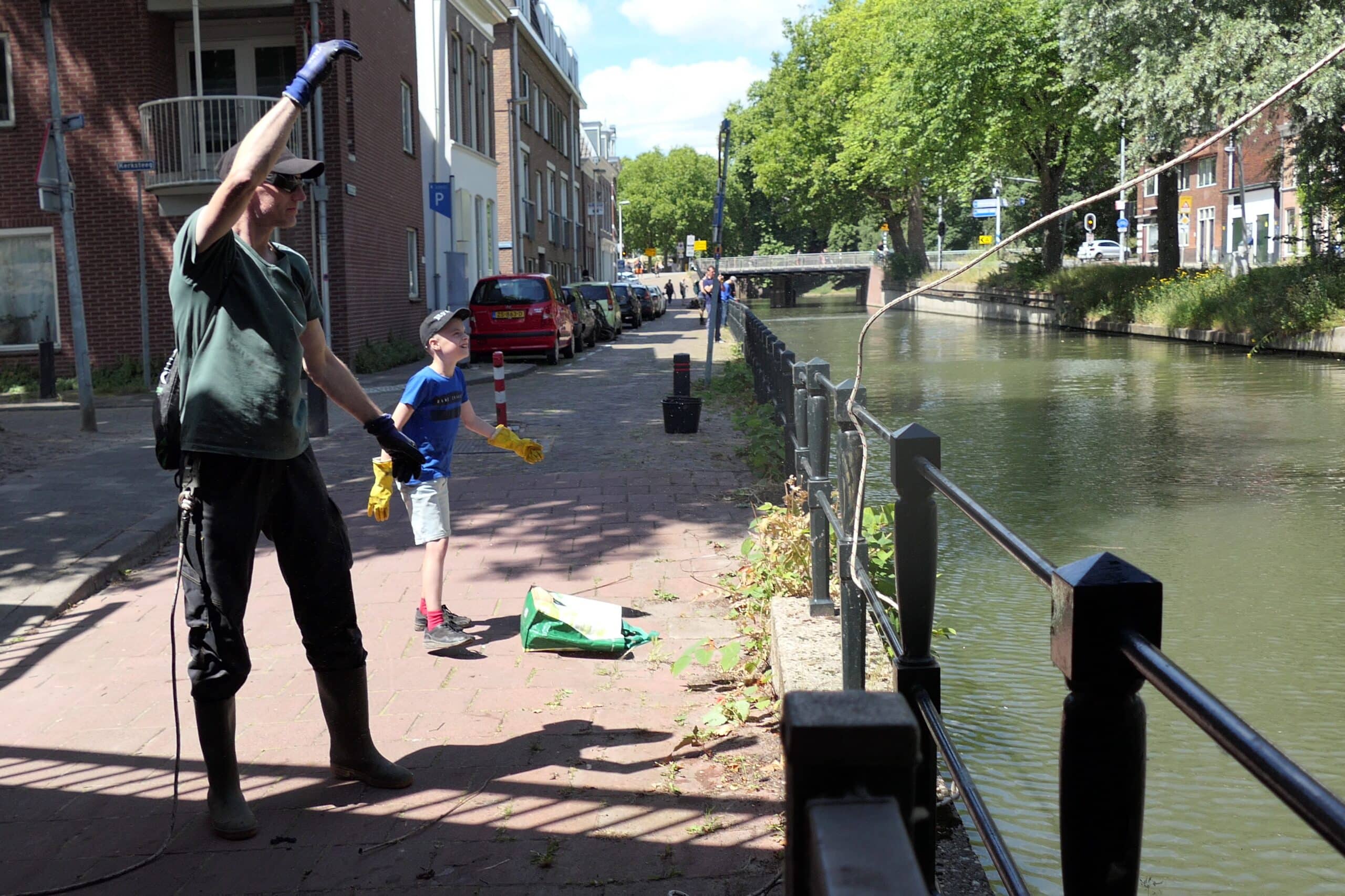 Een vader en blije zoon die een sterke magneet in een gracht gooien tijdens het magneetvissen