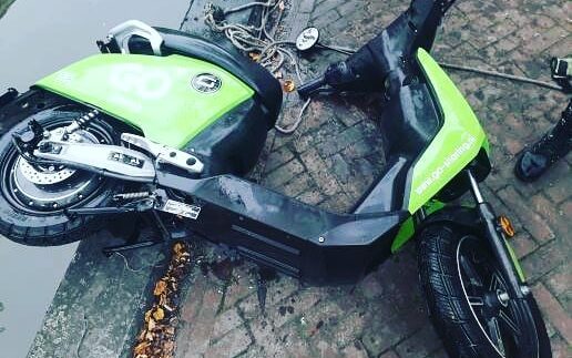 Groene deelscooter uit het water gehaald met een sterke bulldog vismagneet tijdens magneetvissen langs de kade.
