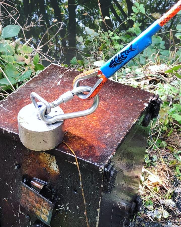 Sterke neodymium vismagneet met oranje touw en karabijnhaak trekt een zware, roestige kluis uit het water.