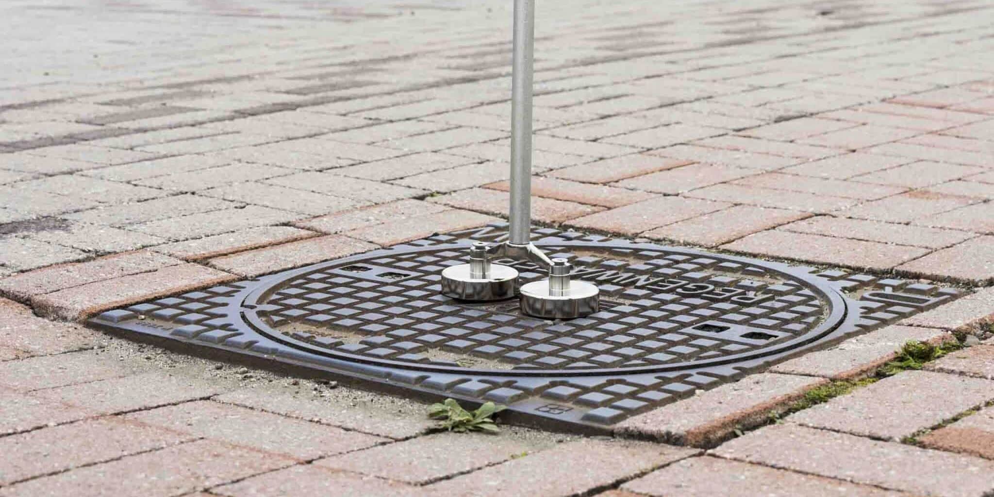 Magnetar puthamer met twee sterke magneten kleeft vast aan een regenwater putdeksel