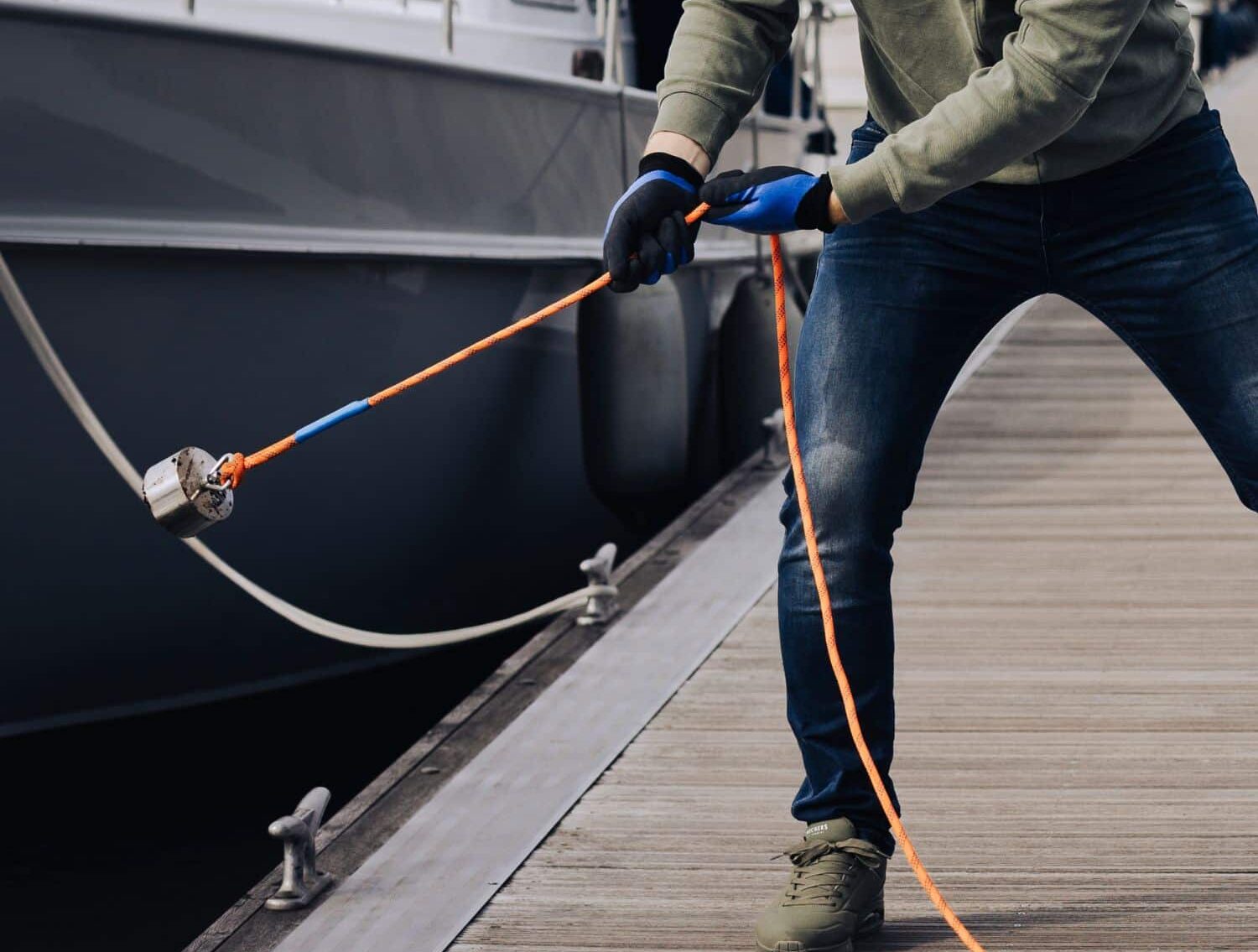 Een man die aan het magneetvissen is in de haven met een 360 magneet en oranje touw